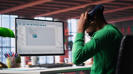 Tech savvy black engineer developing secure online program at home. Surrounded by binary data, freelancer works on interface design, script optimizations and network systems. Camera A.