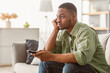 © Prostock-studio - Bored African American Man Watching Boring TV Switching Channels Holding Television Remote Controller Sitting On Sofa At Home. Side View Shot Of Discontented Televiewer