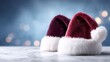 © BOJOShop - Two plush Santa hats with white trim sit on a marble surface against a blurred bokeh background