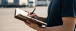 © Renderis - Person writing in a notebook with trucks in the background outdoors, styled to represent cargo documentation, transport management, and logistics operations.