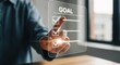 © Farzana - A person's hand touching a virtual screen with a goal checklist, symbolizing success, achievement, and business planning in a modern corporate environment