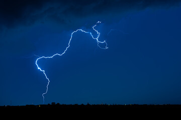 Wall Mural - a bright lightning bolt cuts through a dark sky, showcasing the raw power of nature at night