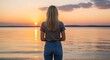 © Bery - Young woman contemplating a serene sunset over calm waters radiating peace and tranquility