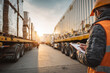 © EricMiguel - Warehouse worker inspecting and documenting cargo on trucks during sunset in logistics and transportation hub