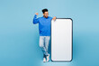 © ViDi Studio - Full body young happy man of African American ethnicity wear sweatshirt casual clothes big huge blank screen mobile cell phone smartphone with area do winner gesture isolated on plain blue background.