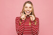 © ViDi Studio - Young smiling satisfied woman wearing red striped sweatshirt casual clothes hold in hand invisible transparent aligners, invisalign dental braces isolated on plain pink background. Lifestyle concept.