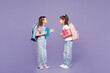 © ViDi Studio - Full body little two friends children school girls 9-10 years old wear casual clothes backpack together hold books talk speak isolated on plain purple background Childhood education lifestyle concept