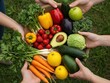 © Sergey - A top-down view of a wooden tray overflowing with diverse, colorful fresh fruits and vegetables, held by several hands over green grass.