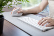 © Alina - Person's hand operates a modern ergonomic vertical mouse and keyboard on a desk pad, emphasizing comfort and efficiency for prolonged remote work
