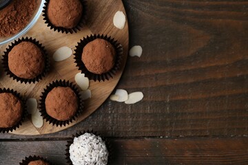 Wall Mural - delicious homemade candies with cocoa powder and coconut flakes on wooden table, flat lay. space for