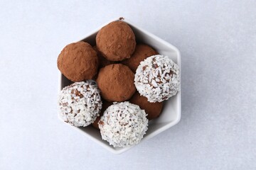 Wall Mural - delicious homemade candies with cocoa powder and coconut flakes in bowl on white table, top view