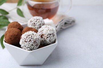 Wall Mural - delicious homemade candies with cocoa powder and coconut flakes in bowl on white table, closeup. spa