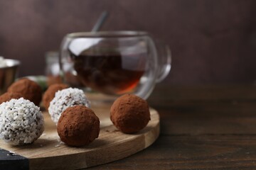 Wall Mural - delicious homemade candies with cocoa powder, coconut flakes and tea on wooden table, closeup. space