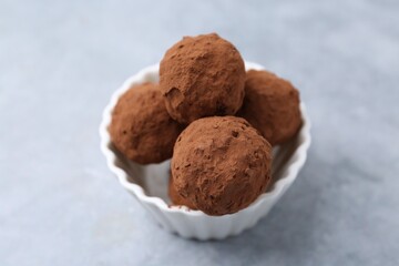 Wall Mural - delicious homemade candies powdered with cocoa in bowl on light table, closeup