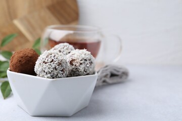 Wall Mural - delicious homemade candies with cocoa powder and coconut flakes in bowl on white table, closeup. spa