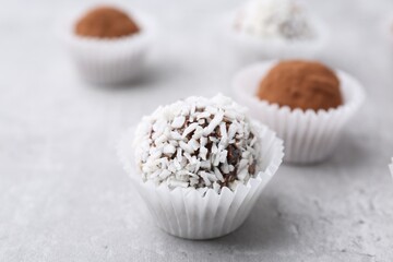 Wall Mural - delicious homemade candies with cocoa powder and coconut flakes on light grey table, closeup