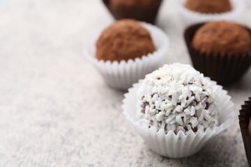 Wall Mural - Delicious homemade candies with cocoa powder and coconut flakes on light grey table, closeup. Space for text