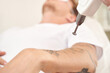 © elenavolf - Young caucasian male receiving tattoo removal procedure with laser device in clinical setting.