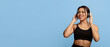 © Prostock-studio - Active free time. Sporty black lady in sports uniform with headphones exercising or dancing, touching wireless headset over blue studio background, empty space, banner