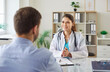 © Studio Romantic - Friendly female doctor sitting at her desk with male patient. Smiling young woman physician or general practitioner in white coat giving medical consultation to patient. Doctor's appointment concept