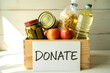 © Graphic Fizz - Wooden crate filled with groceries and a sign that says donate food donation