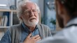 © Attasit - An elderly man with a worried expression discusses his health concerns with a compassionate doctor in a medical office, pointing to his chest to indicate heart issues. The atmosphere is serious yet su