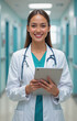 © Rajesh - A smiling, professional female doctor holding a tablet in a hospital corridor.