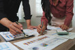 © Phimwilai - Business people analyzing financial charts and graphs at office desk