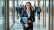 © Olga - Confident businesswoman with folder in office hallway
