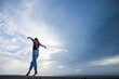 © TrueShot | Westend61 - Woman with arms outstretched balancing on wall in front of sky
