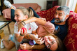 © TrueShot | Westend61 - Father with two playful daughters on couch at home
