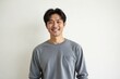 © kineter_ai - Portrait of a happy and confident 40-year-old Korean man with a genuine smile, standing casually against a clean white background.