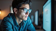 © LabioLoops - A young man wearing glasses stares intently at a computer screen. The computer screen reflects in the lenses of his glasses.
