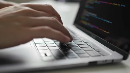 Hands typing on laptop keyboard with code on the screen