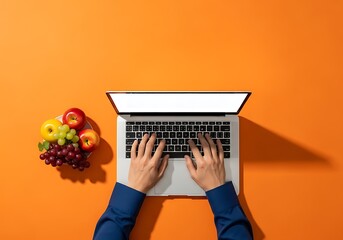 Person's hands typing on a laptop computer with a vibrant orange background and fruit