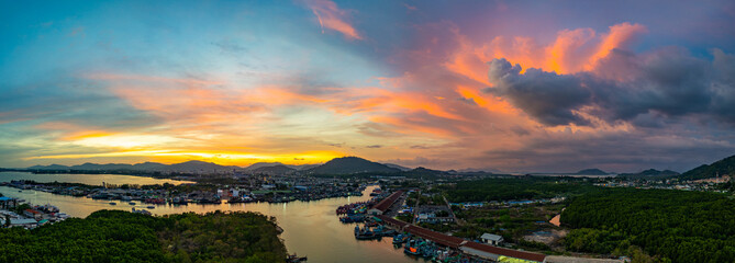 Wall Mural - Aerial view of Stunning sunset featuring fishing port in Phuket. The vibrant sky transitions from soft purples to fiery orange hues, creating a tranquil and picturesque atmosphere.