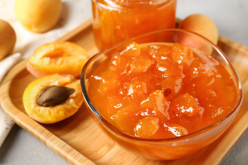 Wall Mural - Tasty apricot jam and fresh fruits on light grey table, closeup