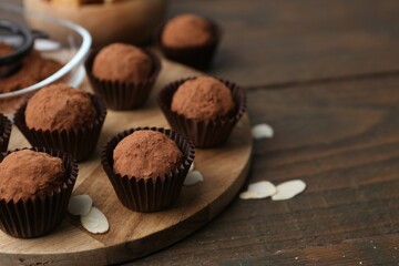 Wall Mural - Delicious homemade candies powdered with cocoa on wooden table, closeup. Space for text