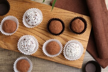 Wall Mural - Delicious homemade candies with cocoa powder and coconut flakes on wooden table, flat lay