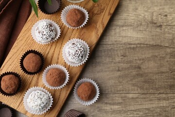 Wall Mural - Delicious homemade candies with cocoa powder and coconut flakes on wooden table, flat lay. Space for text