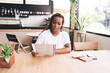 © BullRun - Focused young Black woman reviews documents in cafe, representing analytical precision, concentration, and fusion of offline reading with digital freelance mindset.