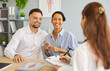 © Studio Romantic - Smiling happy young couple husband and his wife sitting at the desk and talking with family doctor therapist in medical clinic or hospital planning pregnancy. Health care and medicine concept.