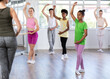 © JackF - Thin teenage girl practicing fifth position of ballet standing in row with others in dance-studio
