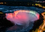 Night Aerial View of Niagara Falls Lit with Colorful Lights and Glowing Water
