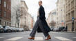 © ViskBx - Woman in stylish coat crossing city street. Her confident stride and modern style create an image of urban sophistication in everyday life.