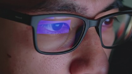 Close-up of a person's face with glasses reflecting a screen