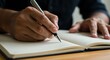 © tembok - Close-up of a person's hands writing with a pen in a notebook