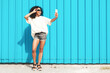 © halayalex - Beautiful woman with afro curls hairstyle.Smiling hipster model in white t-shirt. Sexy carefree female posing in the street near blue wall in sunglasses. Cheerful and happy.Taking selfie photo