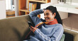 © peopleimages.com - Phone, reading and relax with woman on sofa for social media, text message and communication. Online chat forum, networking and post update with person in living room of home for contact and news