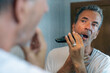 © Laura - Mature man shaving in front of a mirror with an electric razor